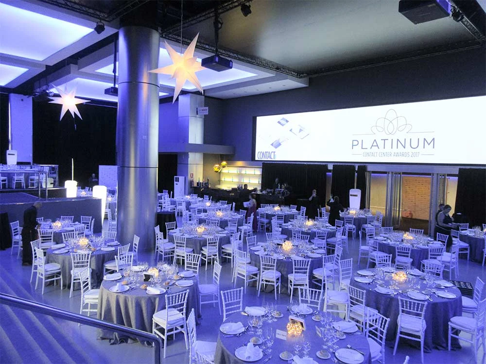 Montaje de banquete con iluminación violeta y pantalla en Teatro Goya